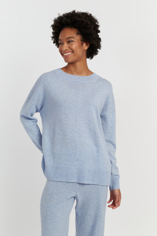 Person wearing a light blue sweater and pants on a white background