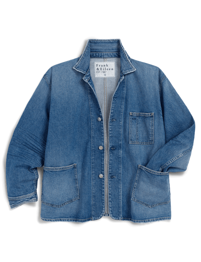 A blue denim work jacket by Frank & Eileen, featuring a button-up front, pointed collar, chest pocket, and two large front patch pockets, shown against a solid black background.