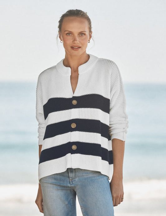 Woman wearing a white and navy striped sweater with a blurred beach background