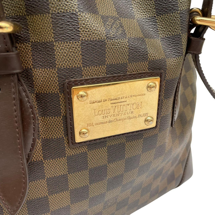 Louis Vuitton brown duffel bag with Damier Ebene pattern and logo plaque details.