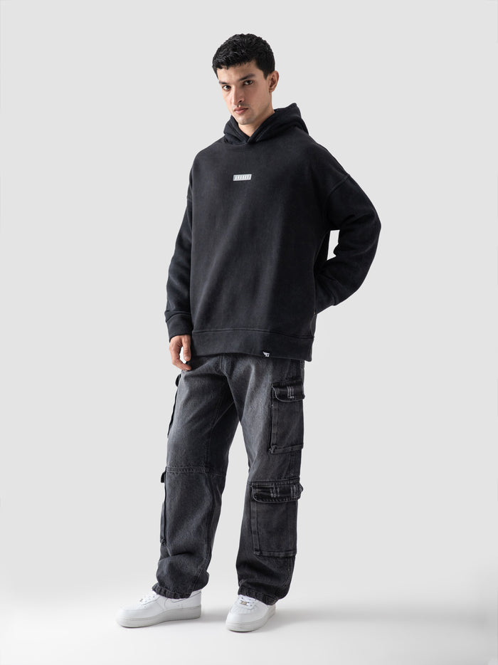 Washed black hoodie male model seated lifestyle shot Pakistan – GROOVY
