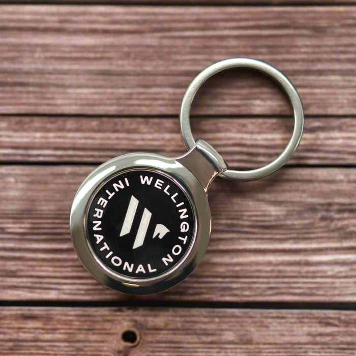 Keychain with Wellington International logo on a wooden desk background