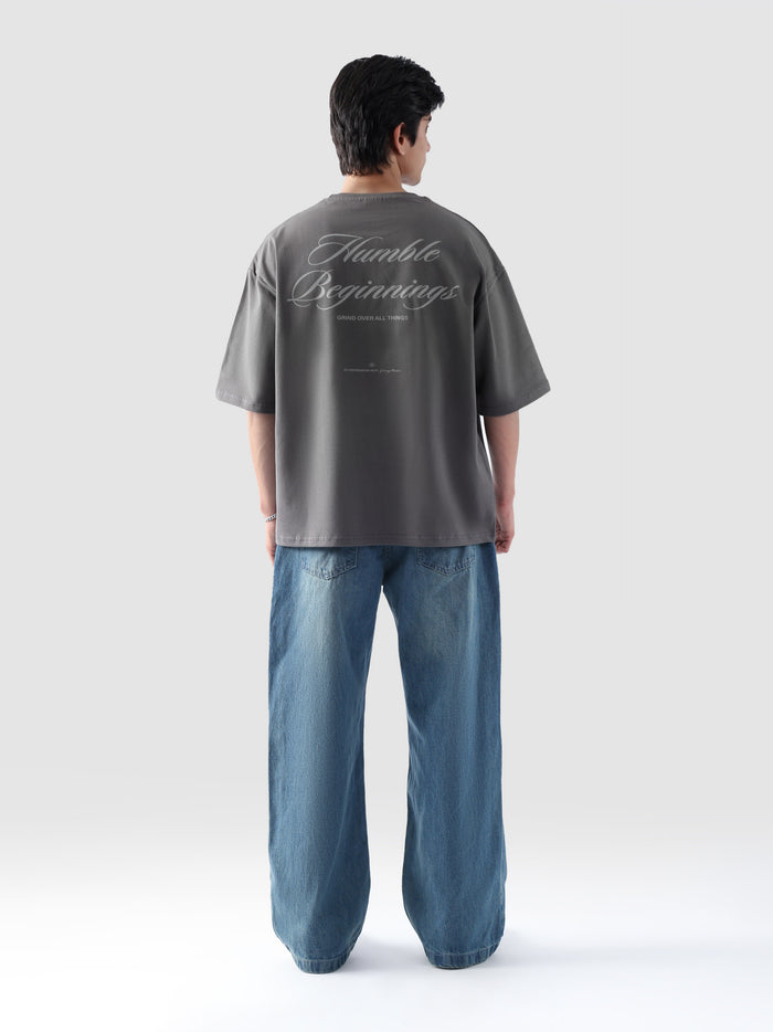 Back view of man wearing grey oversized t-shirt with 'Humble Beginnings' text – baggy streetwear tee by Groovy Pakistan